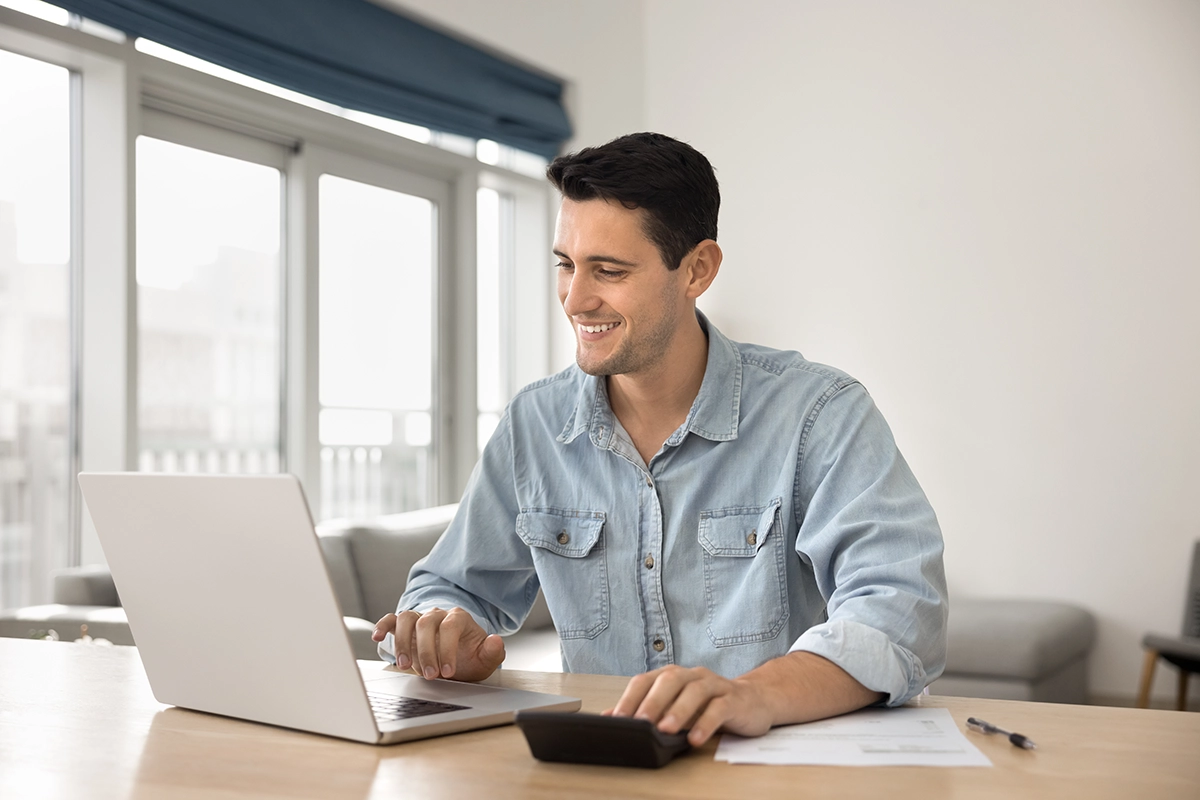 Man sitting at a desk in front of a laptop looking for the best ETFs for Irish investors