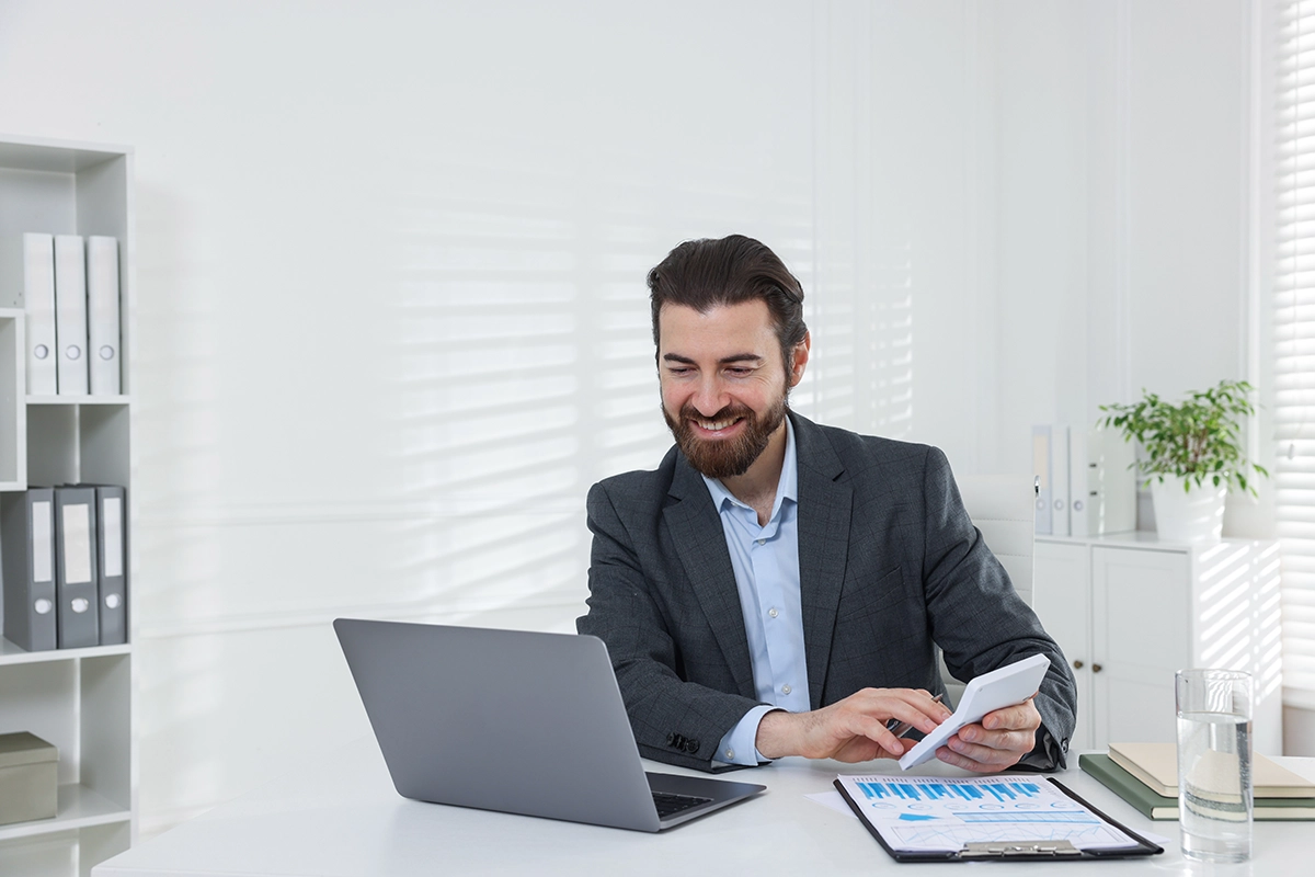 Businessman using a calculator and laptop to calculate his finances.