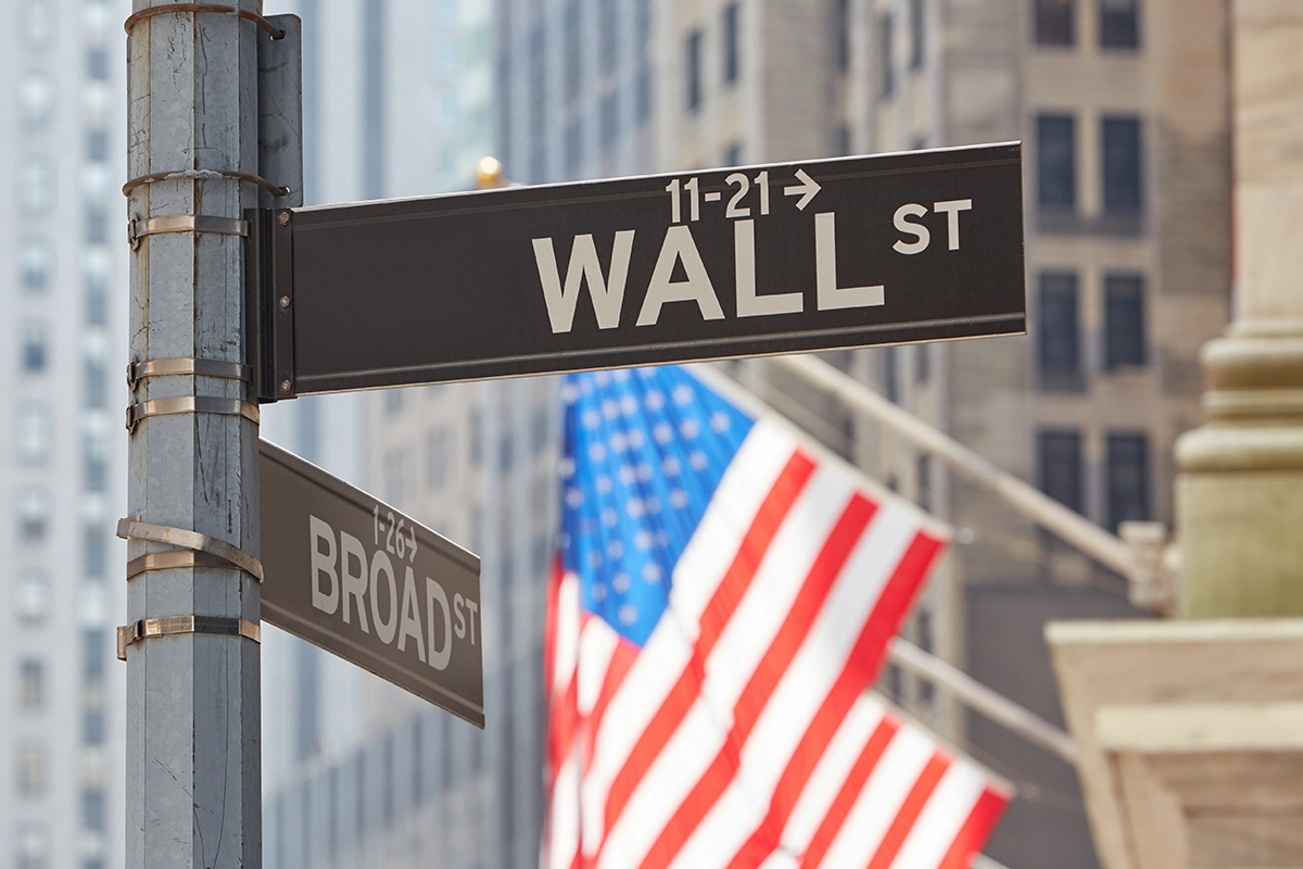 Wall Street sign, associated with synthetic ETF investing, with United States flag in the background